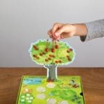 Main d’enfant plaçant cerises sur arbre en carton