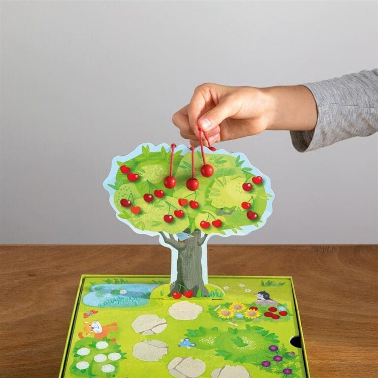 Main d’enfant plaçant cerises sur arbre en carton