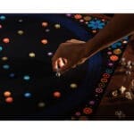 Main jouant avec des perles colorées lumineuses sur tissu noir